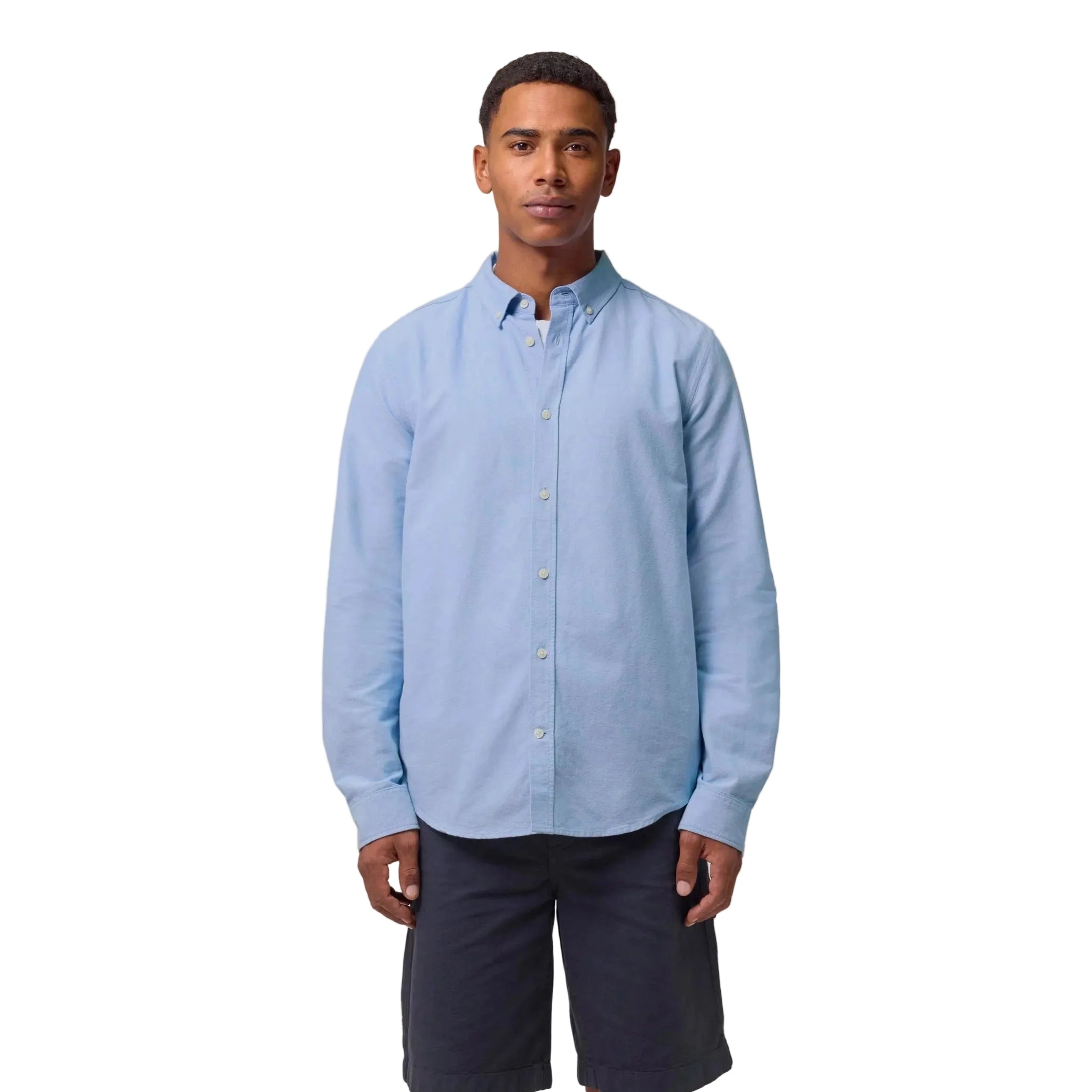 Man wearing a light blue button-up shirt and dark shorts on a white background