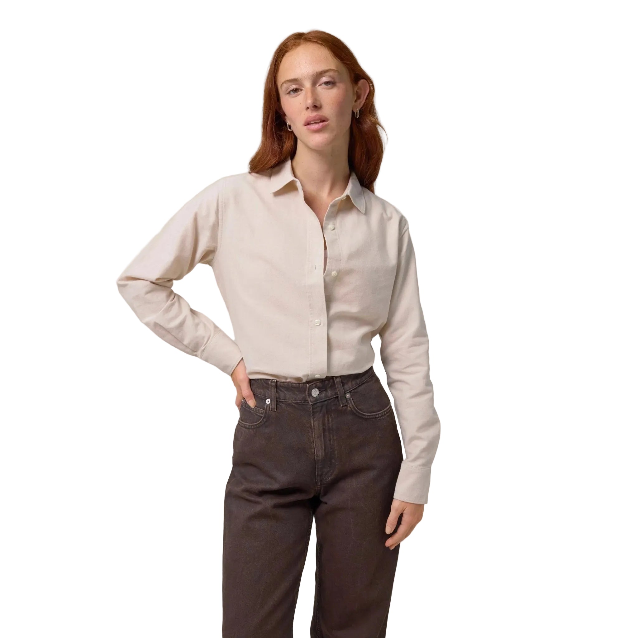 Woman wearing a beige shirt and dark jeans on a white background