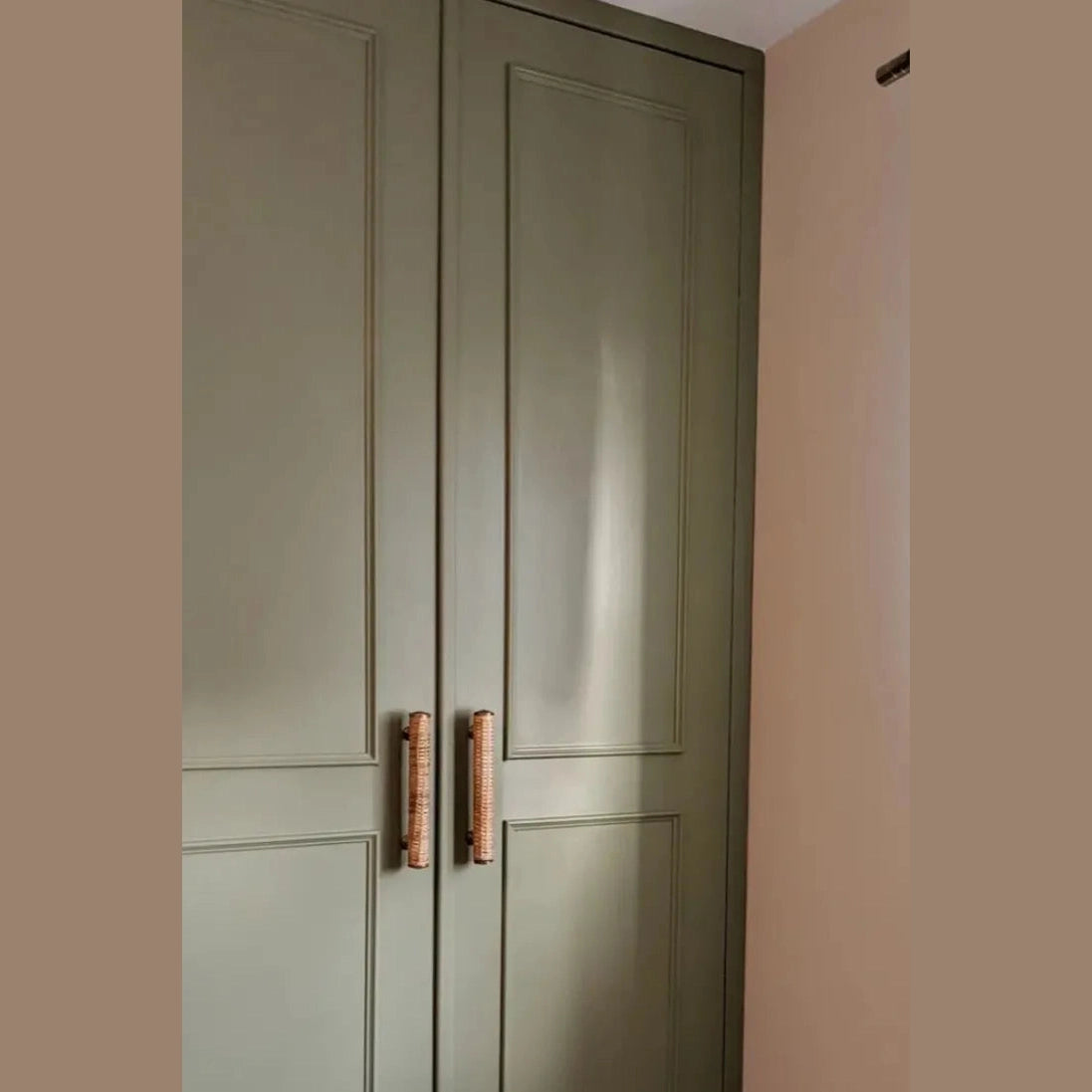 Dunstanburgh rattan bar handles fitted vertically to green panelled wardrobe doors