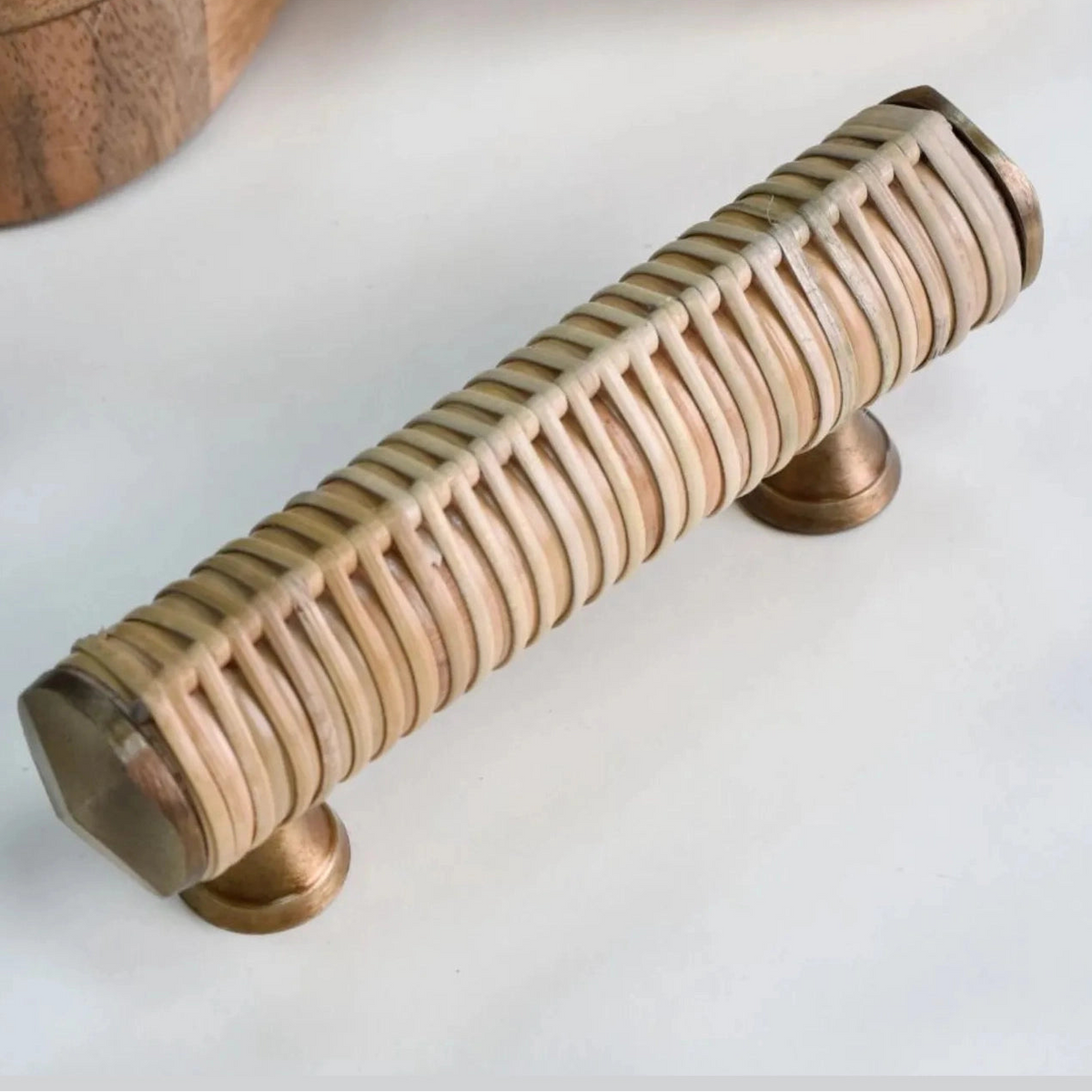 Druridge rattan-wrapped bar handle with metal end caps beside a wooden display prop