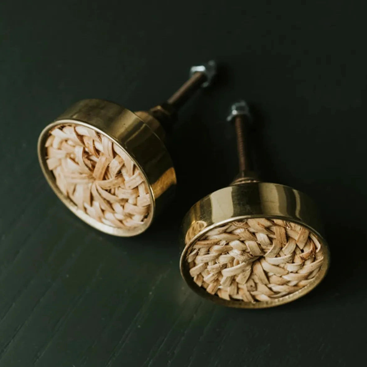 Two Druridge round knobs with woven rattan centres and metal rims on a dark background