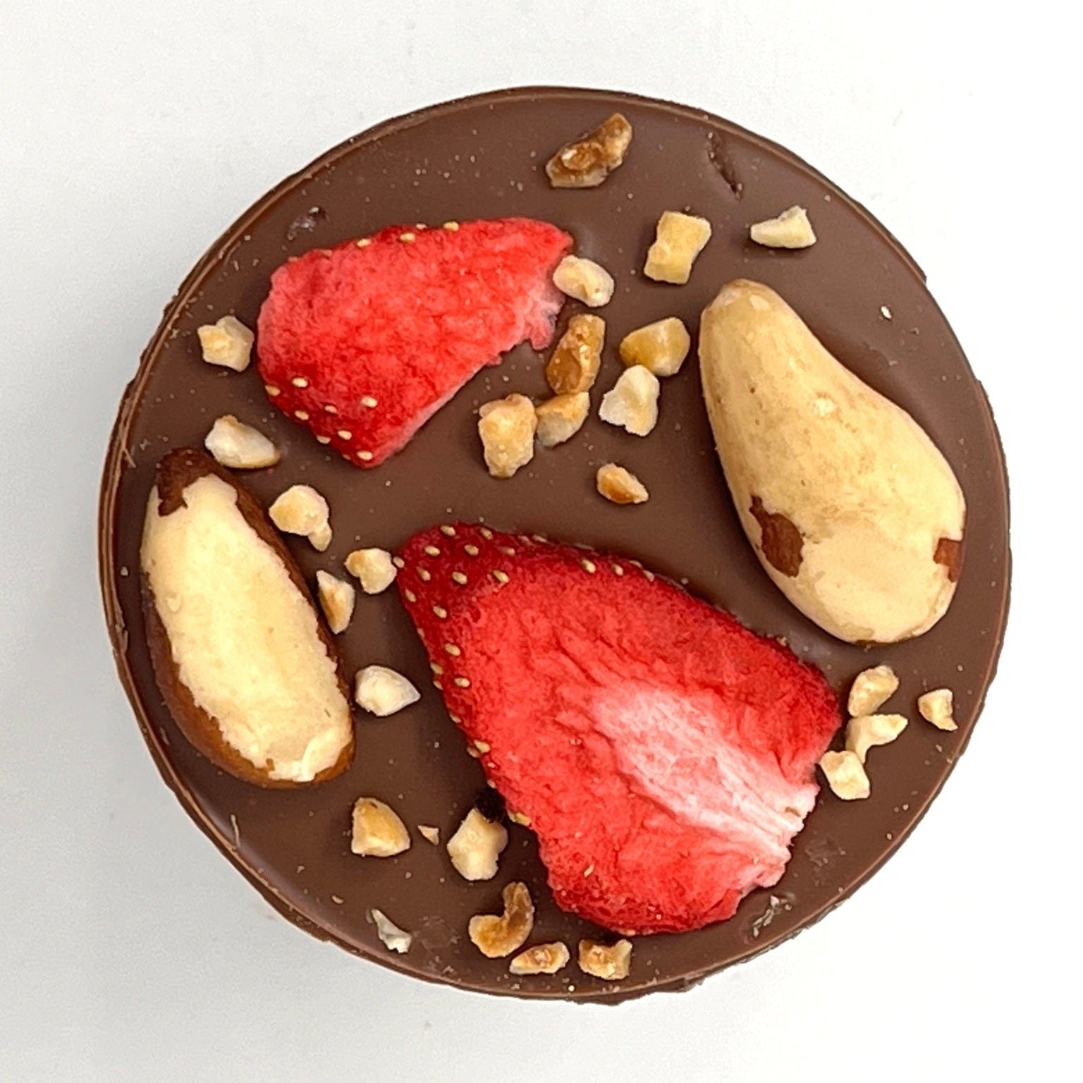 Chocolate disc with strawberries and nuts on a white background