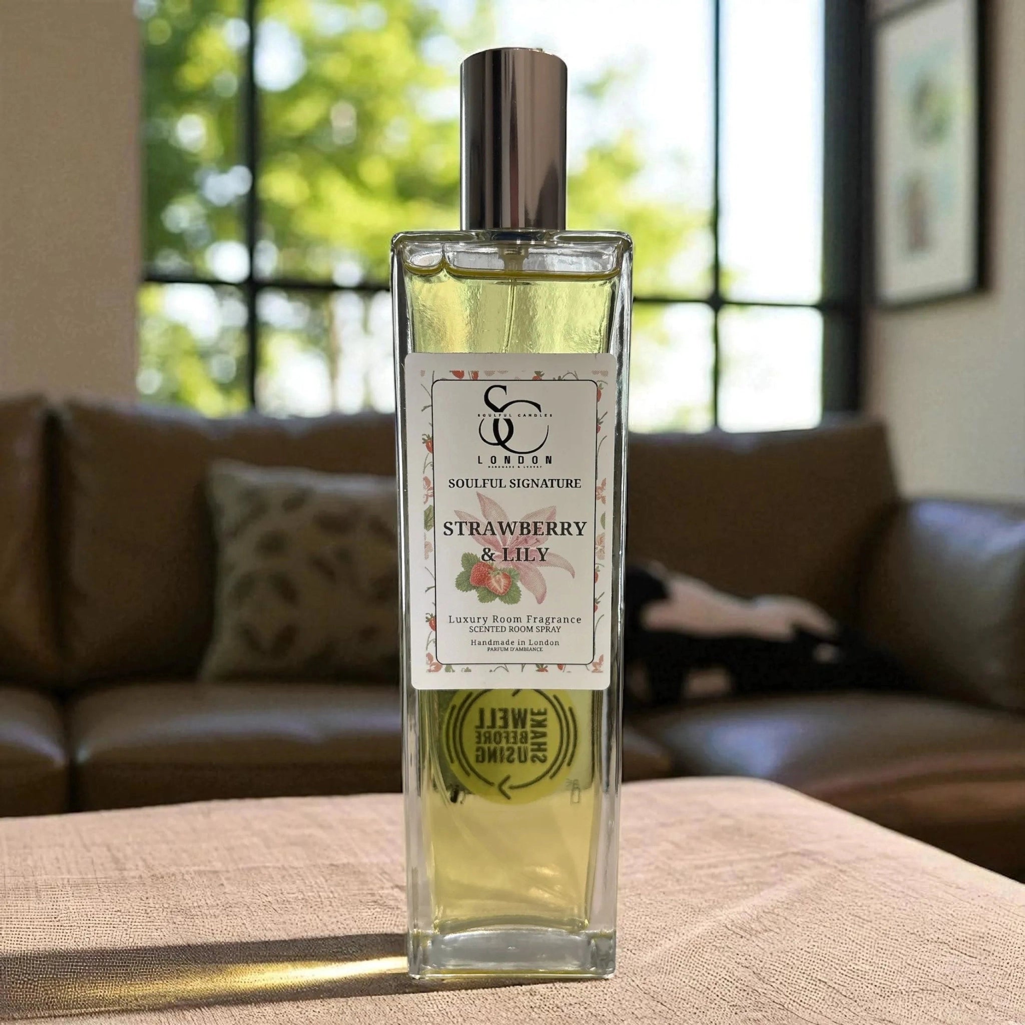 Bottle of strawberry and Lily room spray on a surface with a blurred background