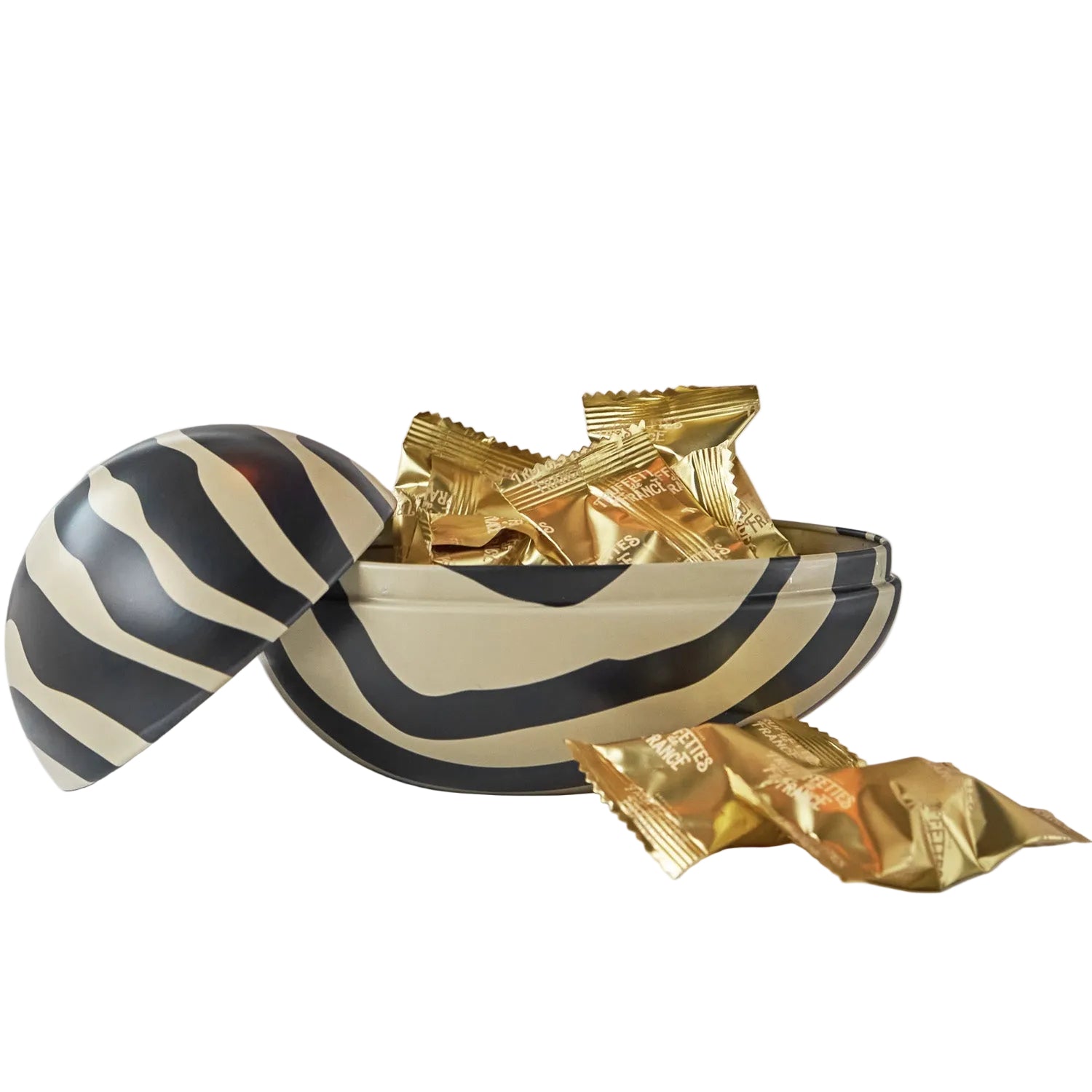 Decorative Easter egg with black and white stripes filled with gold-wrapped candies on a white background