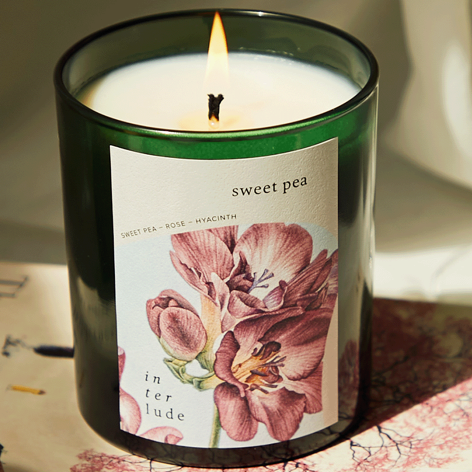 Candle with a floral label on a surface with a blurred background