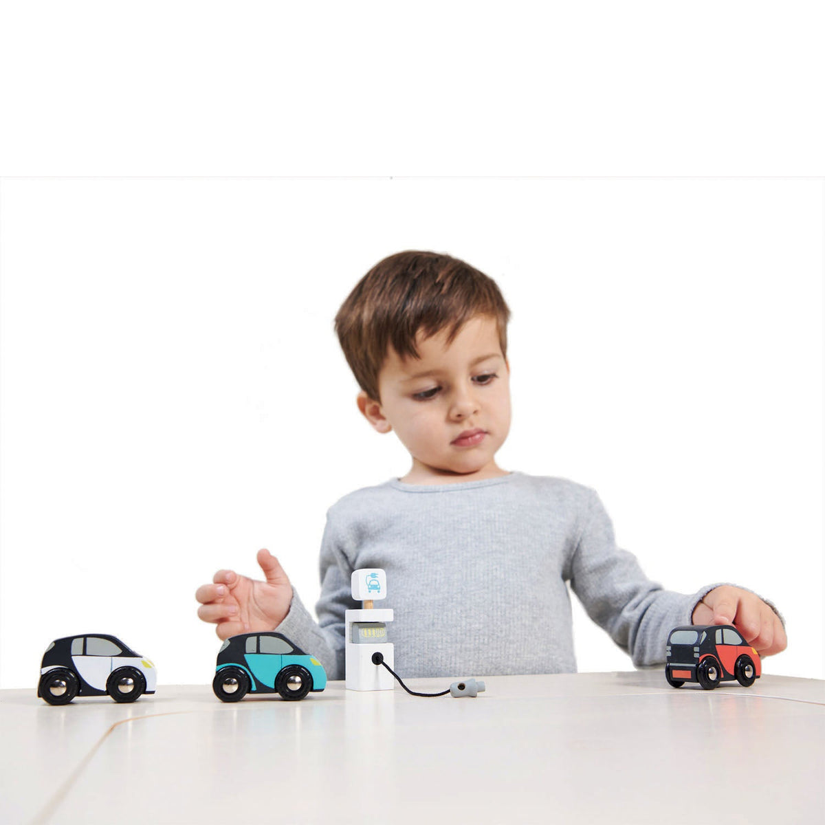 Child playing with Tender Leaf Smart Car Set cars and pretend charging unit on a table