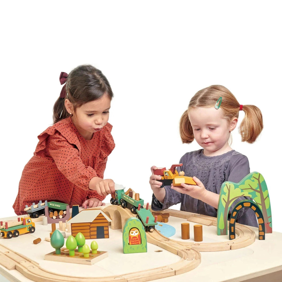 Two children playing with a wooden train set on a white background