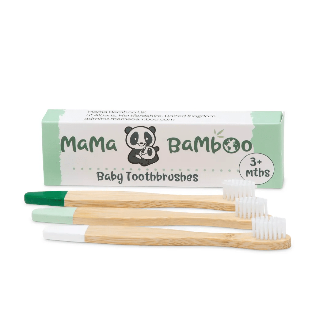 Three Mama Bamboo baby toothbrushes with bamboo handles, coloured tips and white bristles beside their cardboard box