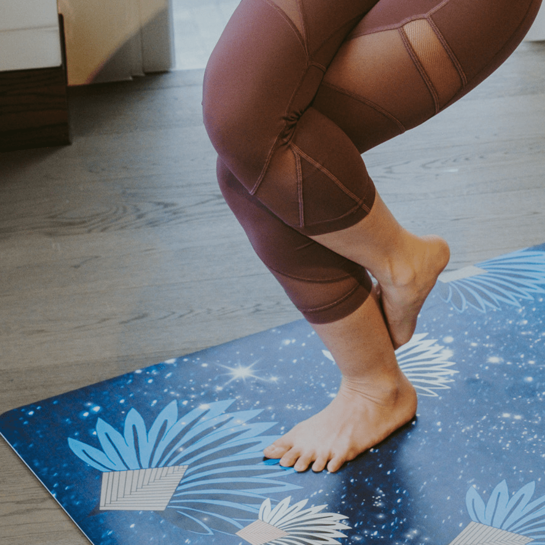 Person wearing maroon leggings on a blue yoga mat with floral designs.