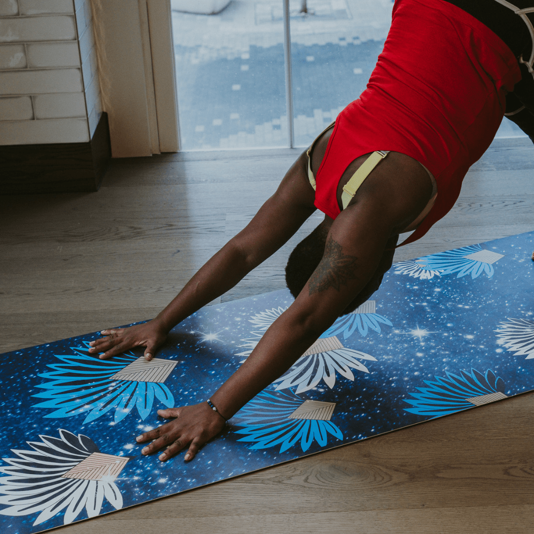 Person in a red outfit performing a yoga pose on a blue floral-patterned mat.
