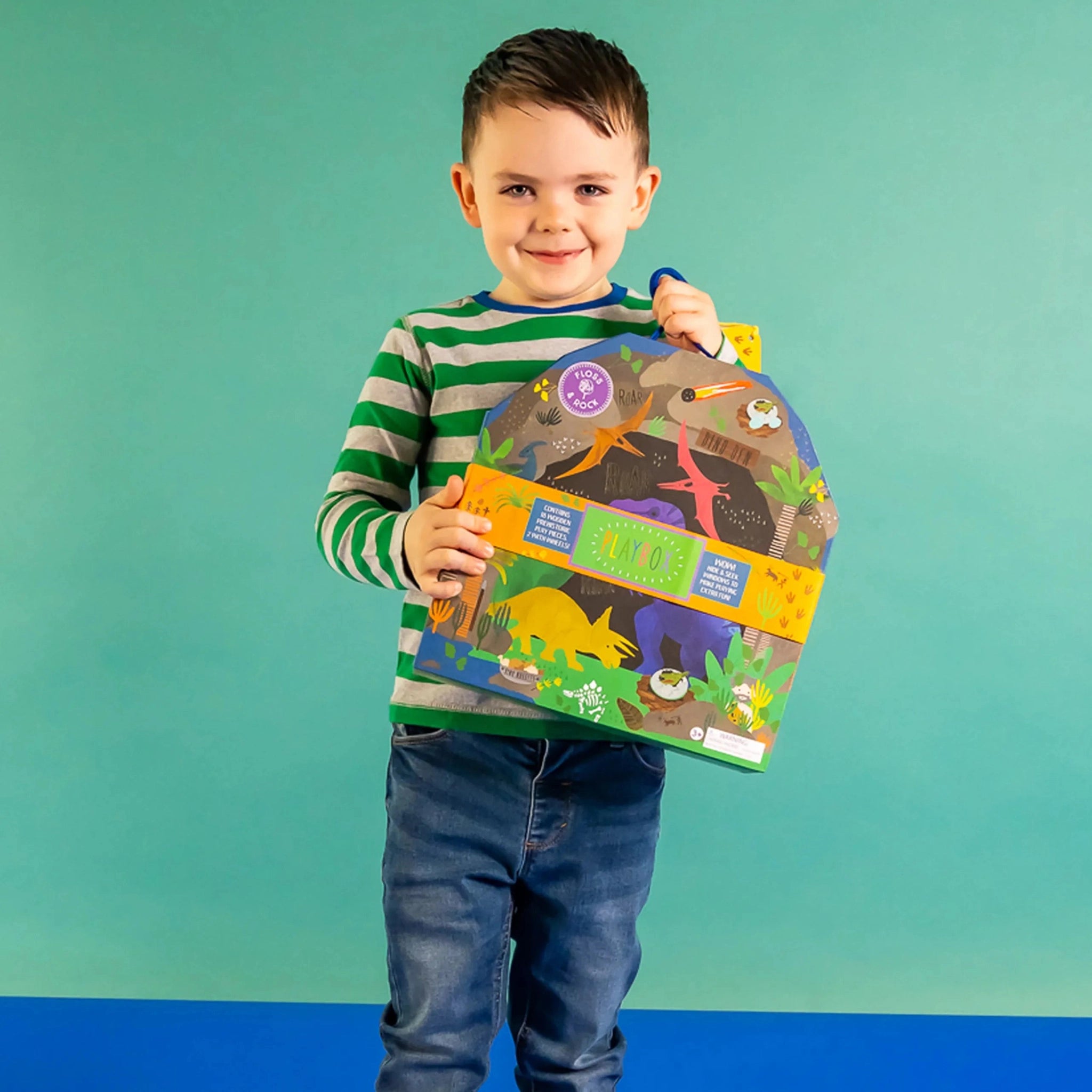 Child holding a dinosaur playset with animal illustrations against a teal background