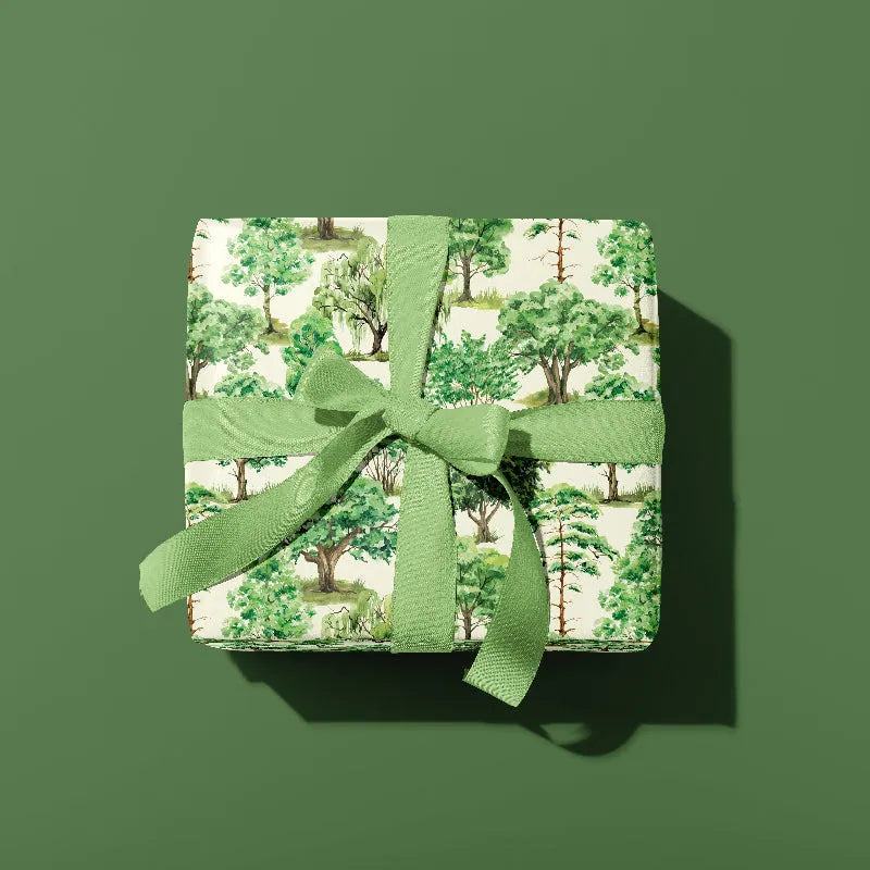 Gift box with green ribbon and forest pattern on a green background