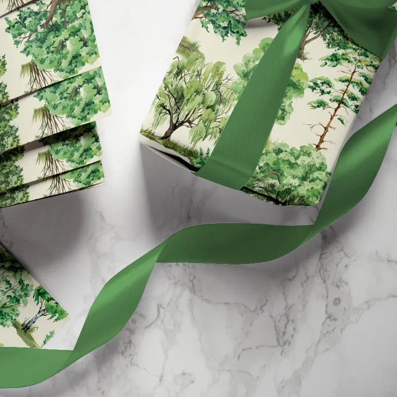 Gift wrapping with green ribbon and forest pattern on a marble surface
