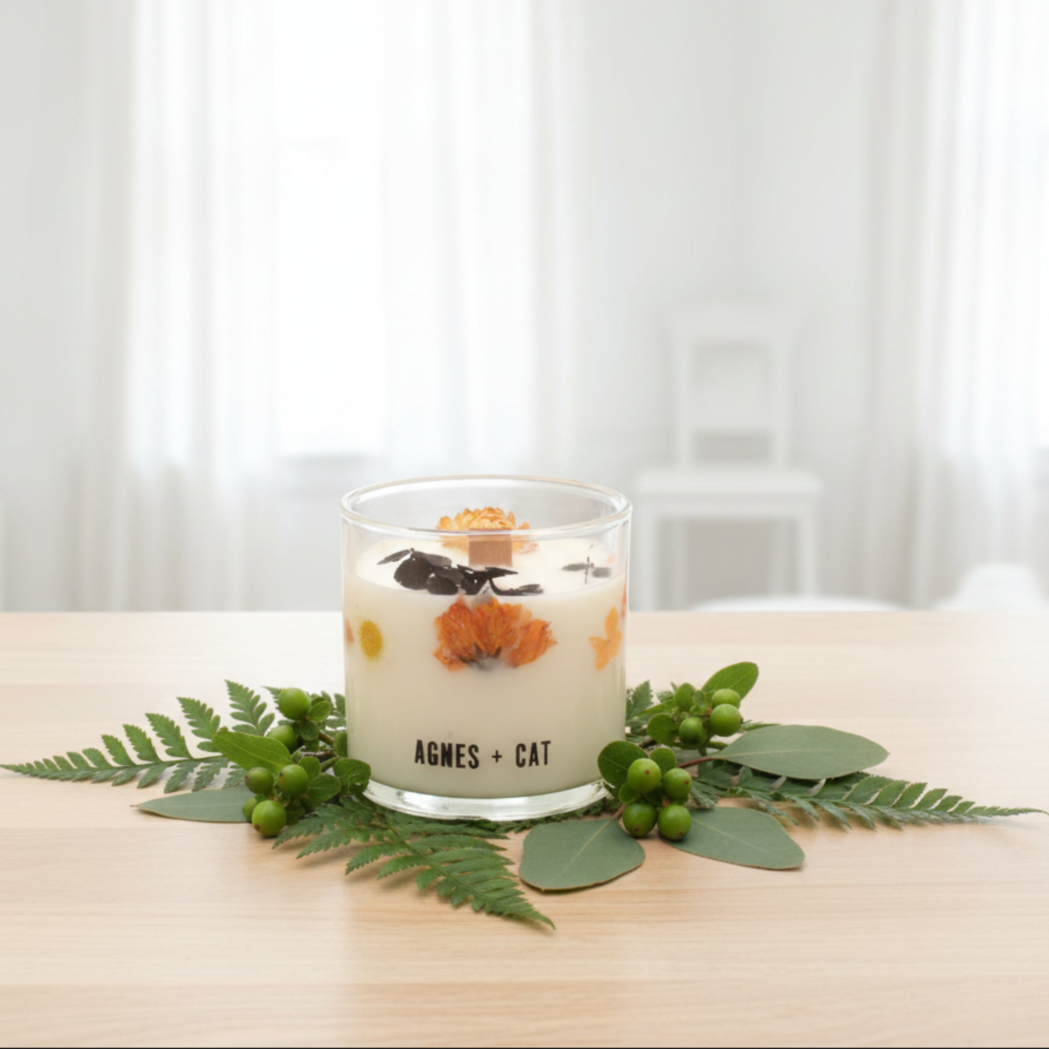 Decorative candle with flowers and leaves in a glass container on a white background