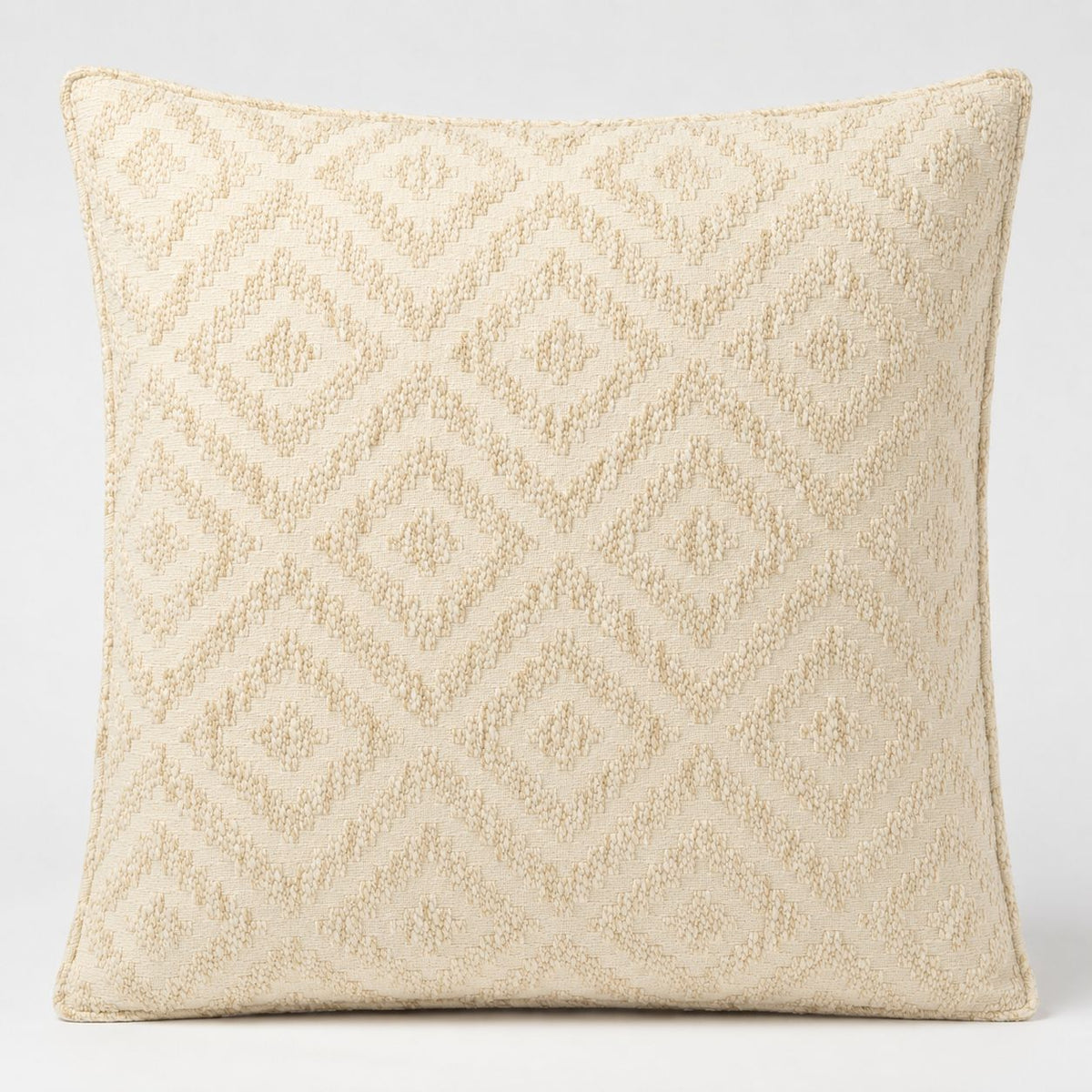 A square throw pillow in a textured cream and beige fabric with a woven geometric diamond pattern, shown against a plain light gray background.