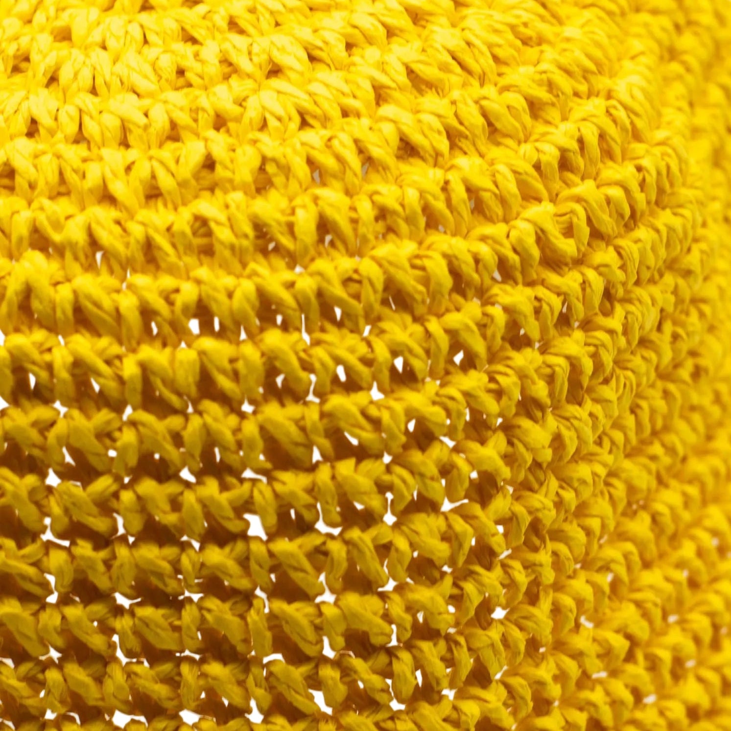 Close-up of a yellow straw fabric hat with a textured pattern.
