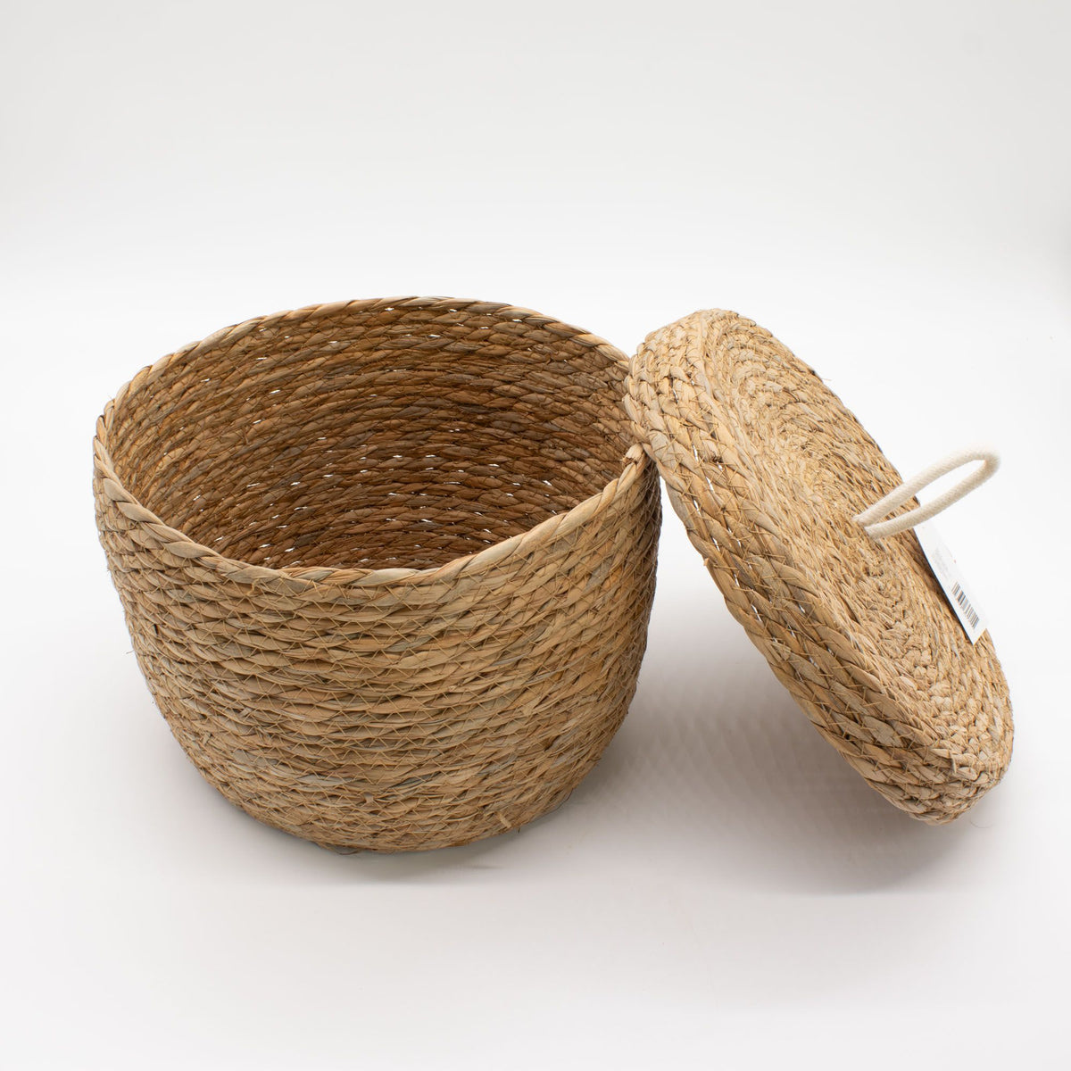 Round woven basket showing its interior, with the lid leaning against the side