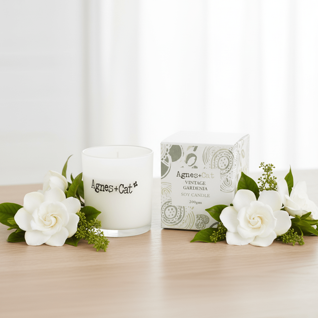 Candle and packaging with 'Agnes & Cat' branding on a wooden surface with flowers.