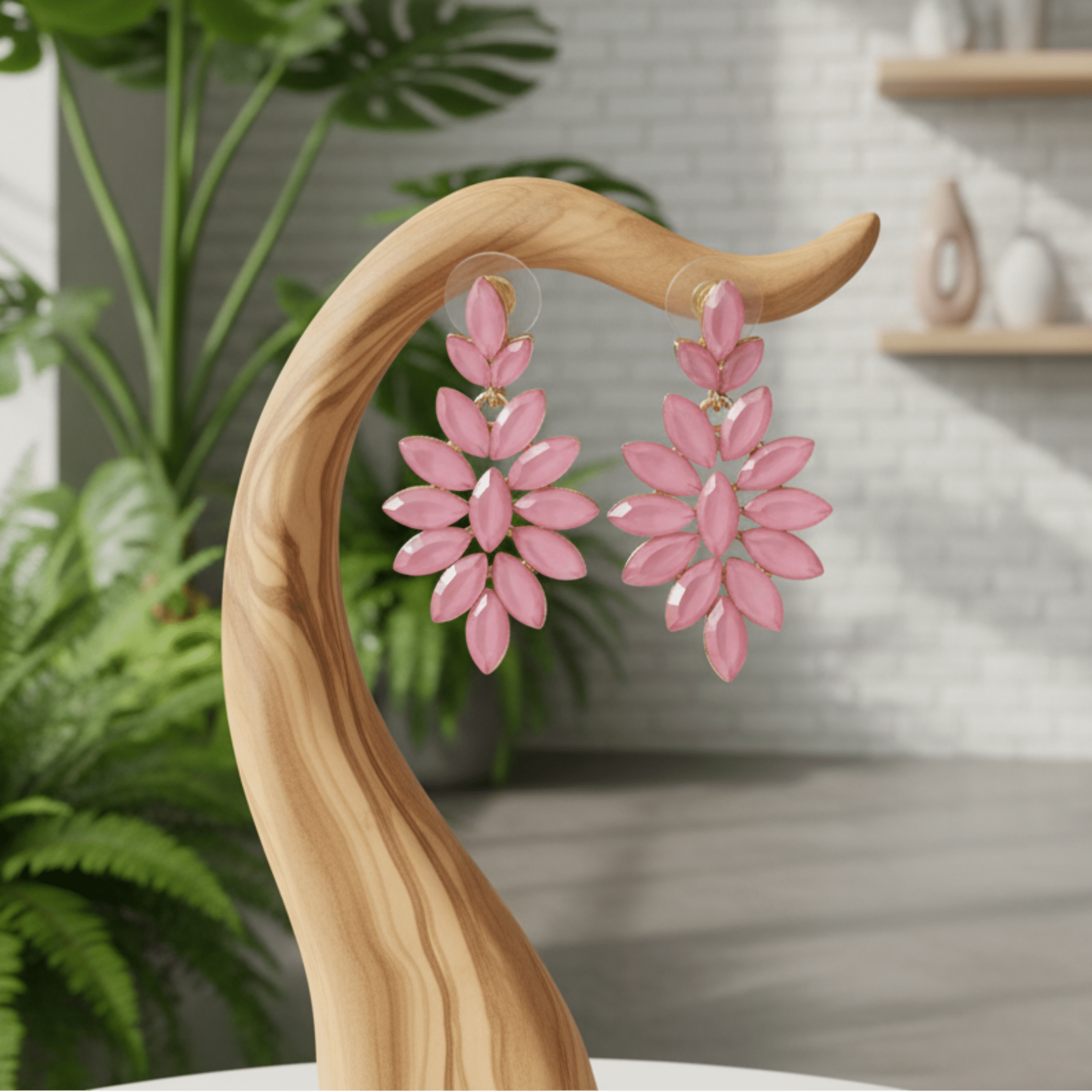 Pink long drop earrings on a wooden stand with plants indoor background