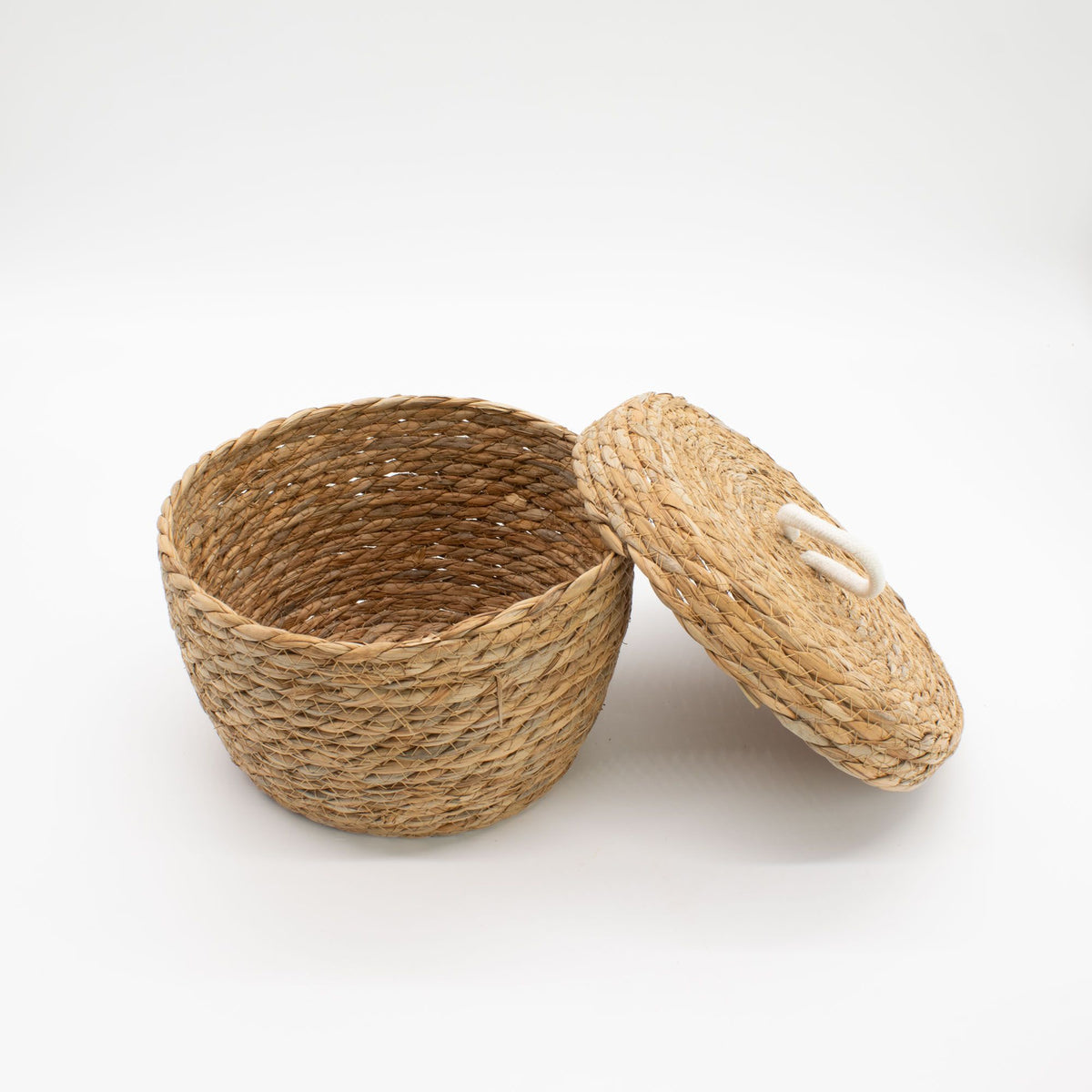 Natural woven basket with its white-loop-handled lid resting at an angle