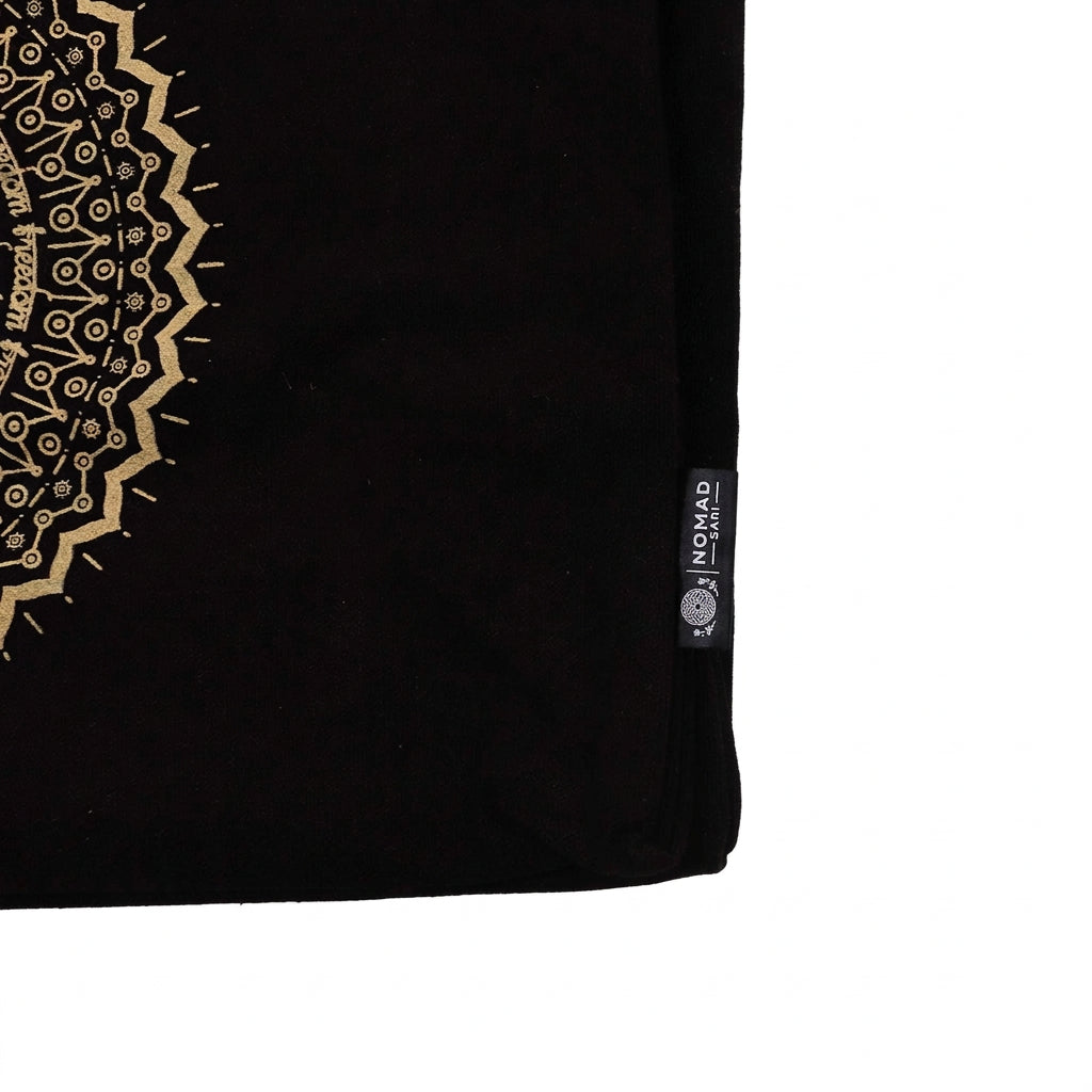 Close-up of a Nomad Sari label on the side of a black tote bag with a gold mandala design.