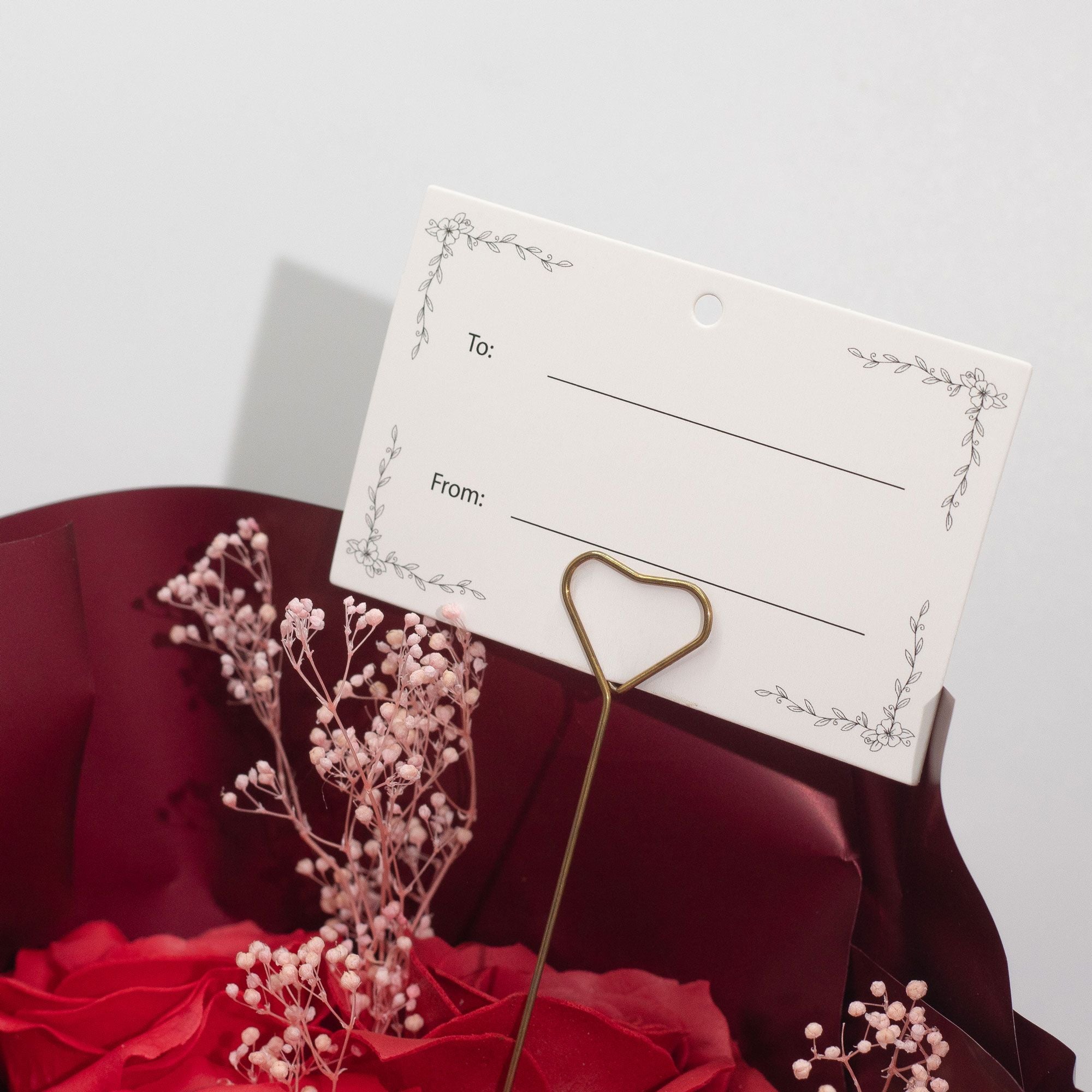 Gift tag with 'To' and 'From:' fields on a red fabric background with soap flowers.