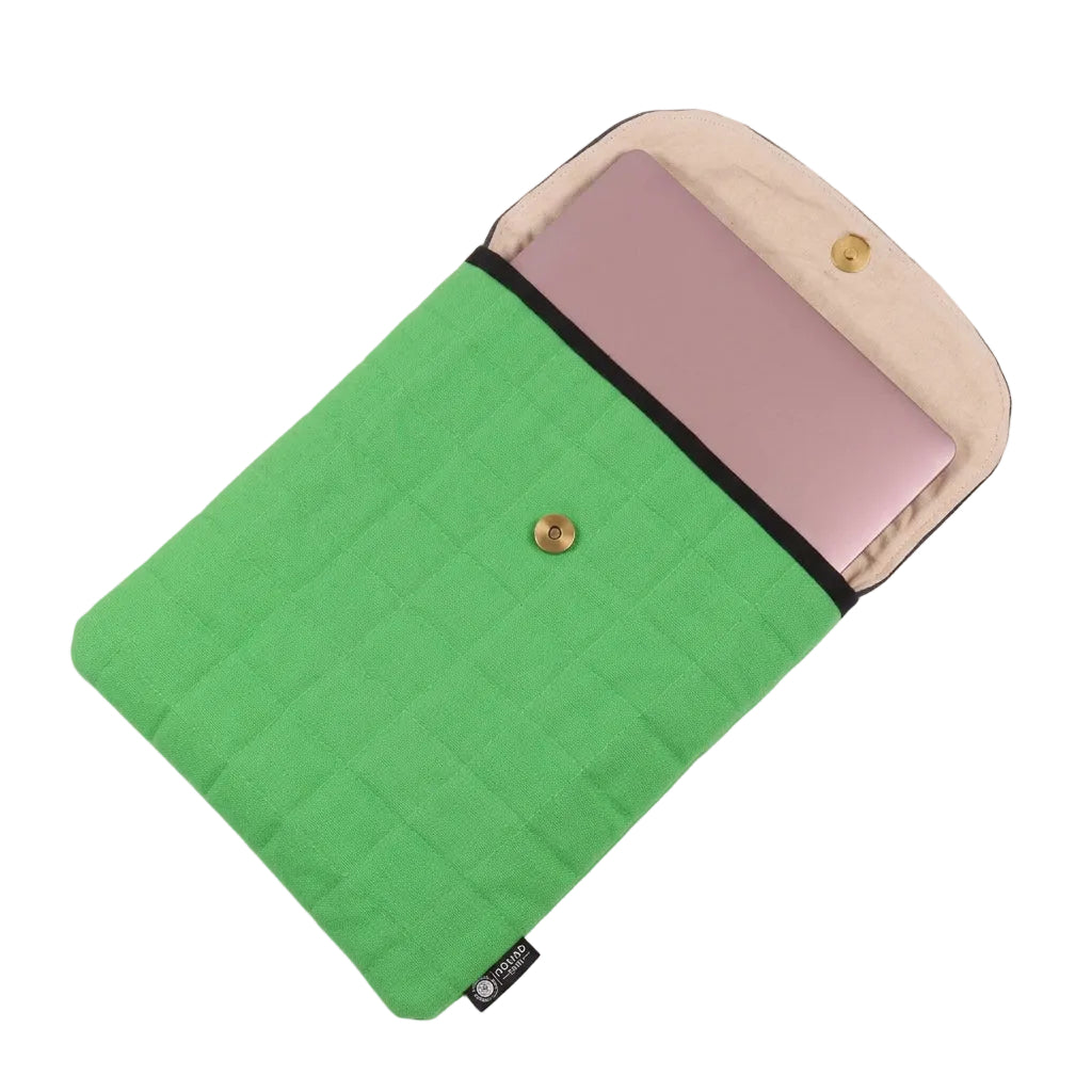 A green quilted laptop sleeve with a beige interior lining and a black trim, shown open with a pink laptop inside. The sleeve features a magnetic fastening closure and a small black brand tag at the bottom corner.