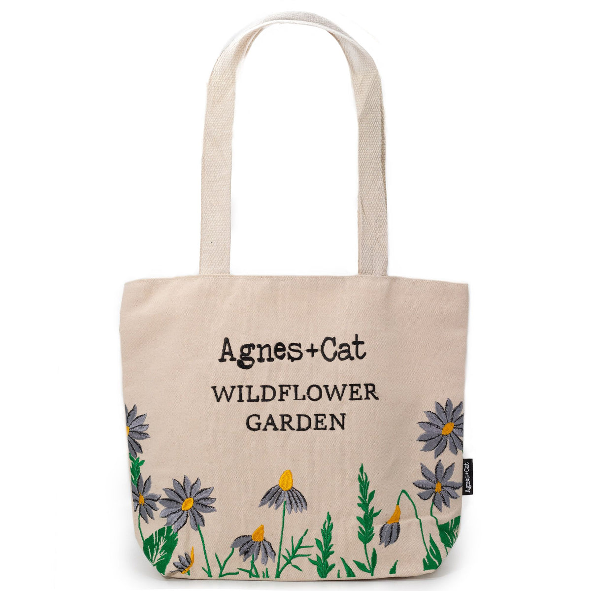 A natural cream coloured tote bag with floral designs and 'Agnes + Cat Wildflower Garden' text on a white background