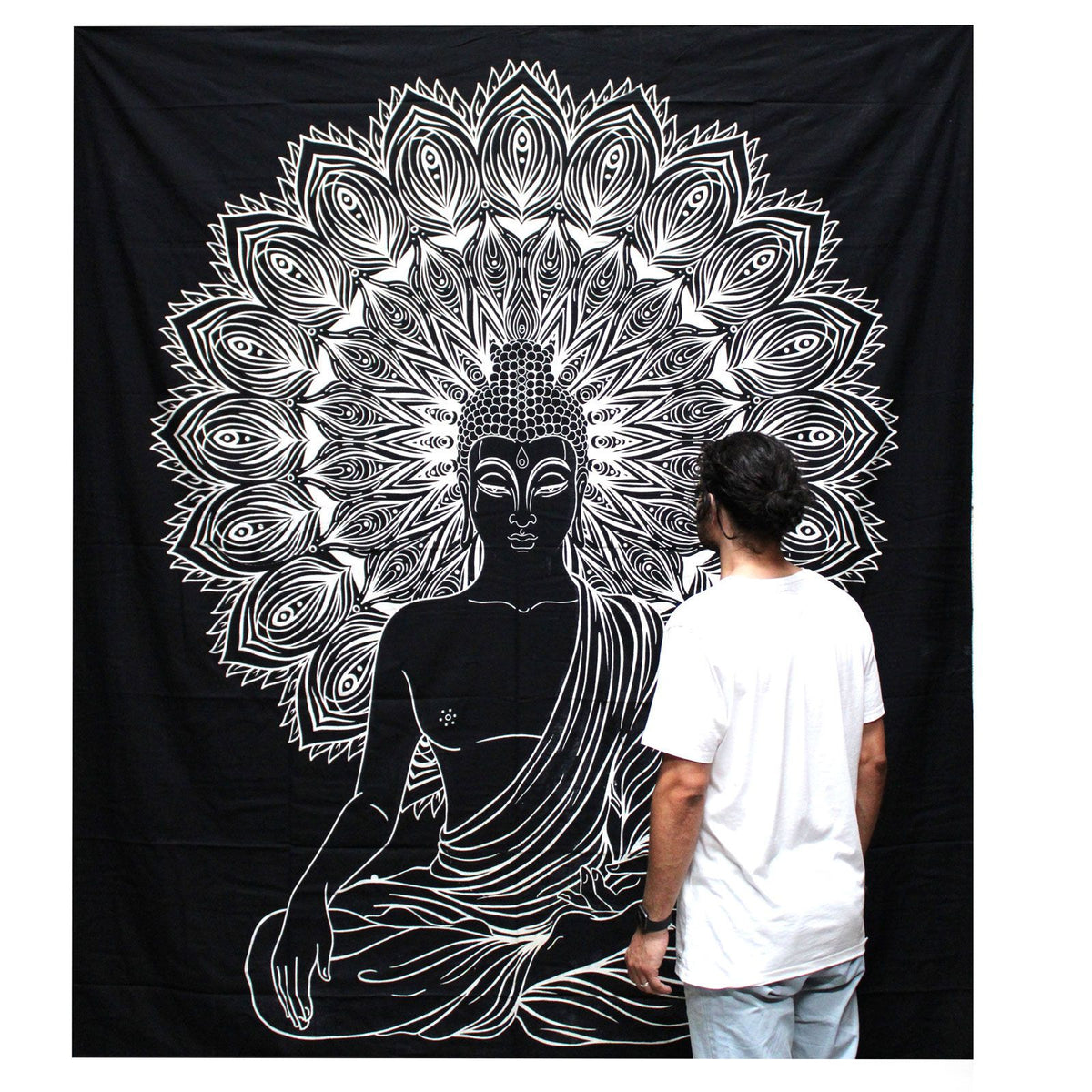 A person standing in front of a black wall hanging with a white Buddha design