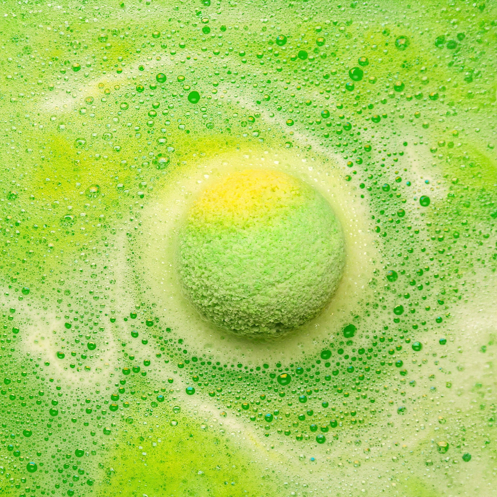 Close-up of a green bath bomb fizzing in water.