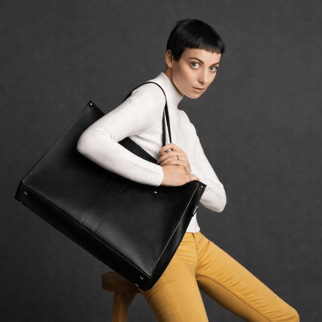 Model carrying the Zatchels black leather shopper over the shoulder against a dark background