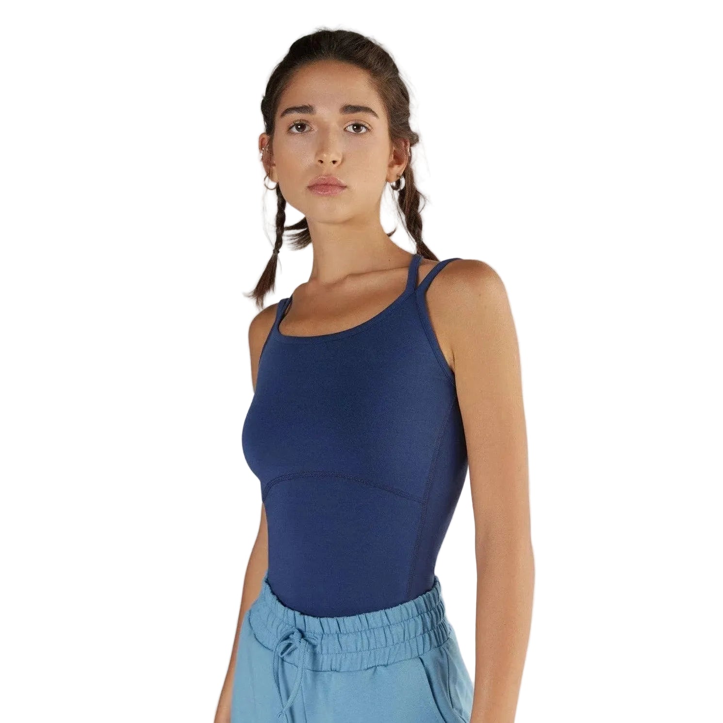 Woman wearing a blue tank top and light blue pants against a white background