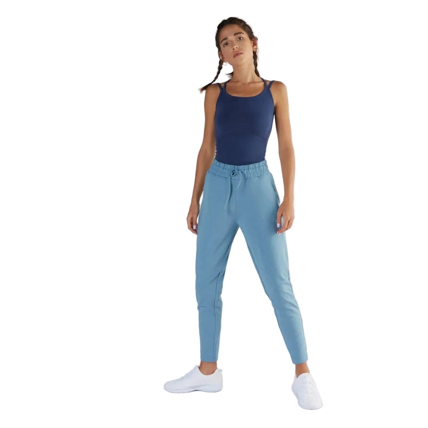Woman wearing a navy tank top and light blue jogger pants on a white background