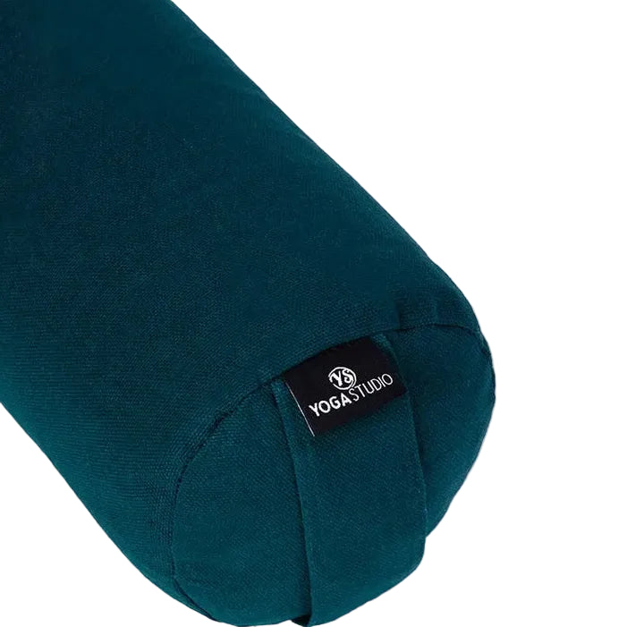 A close-up of a dark teal yoga bolster pillow with a black fabric brand tag reading 'YOGA STUDIO' on a clean white background.