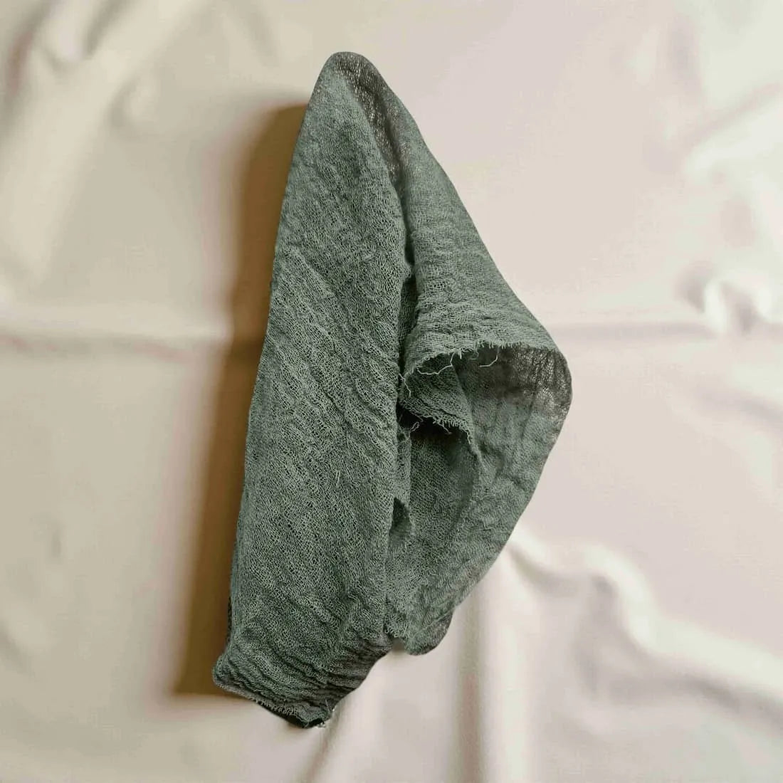 Green textured fabric gift wrap on a white surface