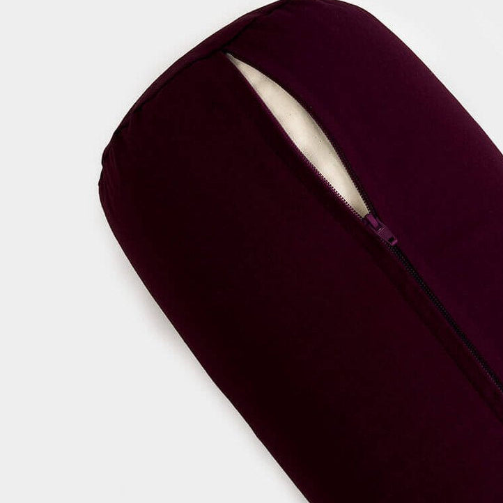 Dark red yoga bolster pillow on a light grey background