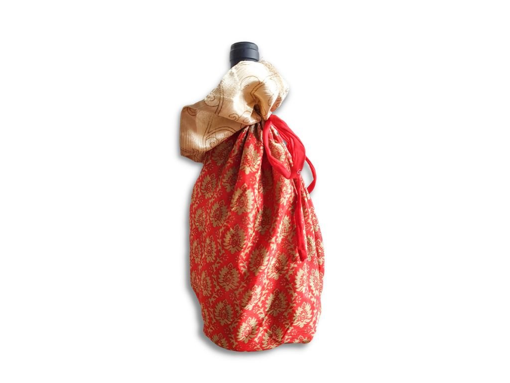 Decorative bottle wrapped in red and gold fabric on a white background