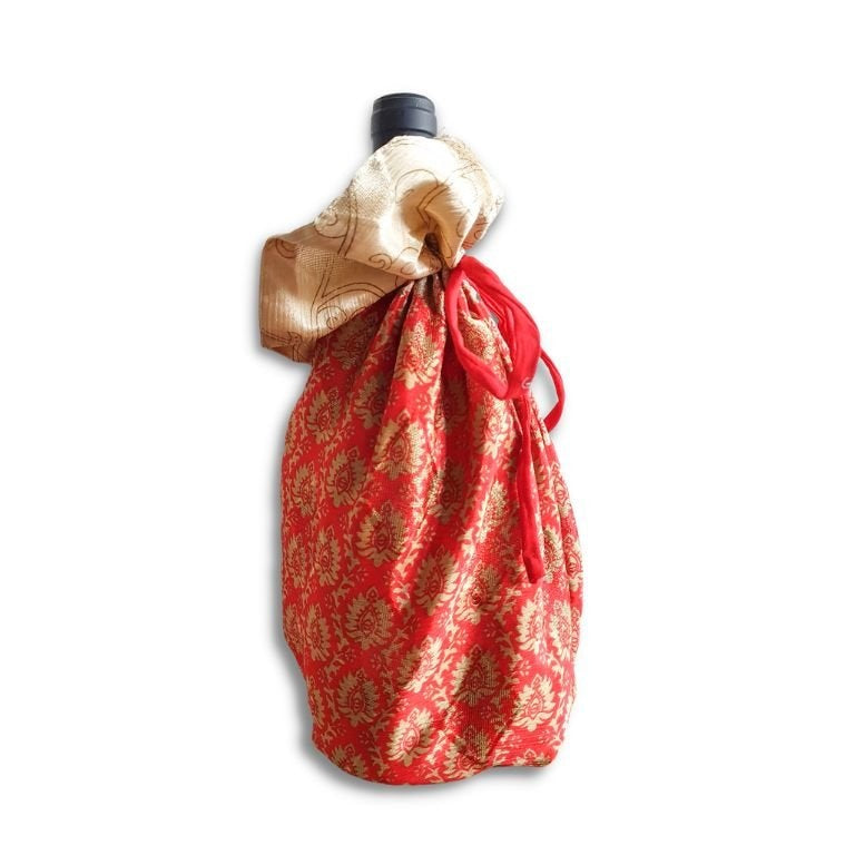 Decorative bottle wrapped in red and gold fabric on a white background