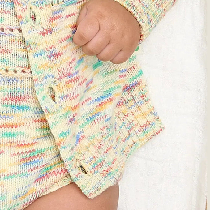 Colourful knitted organic cotton baby outfit with a close-up of a hand holding it.