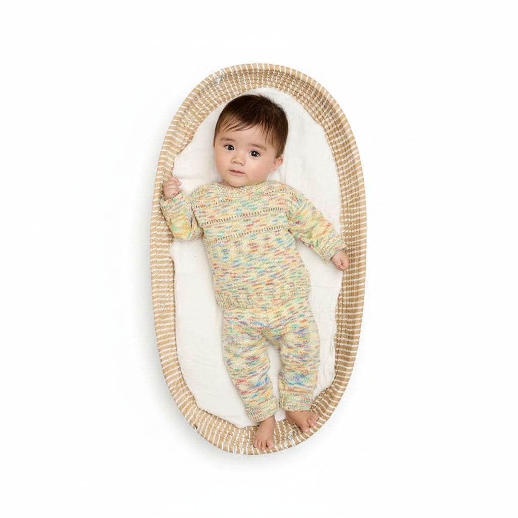 Baby in a colourful organic cotton outfit lying on a woven basket with a beige background