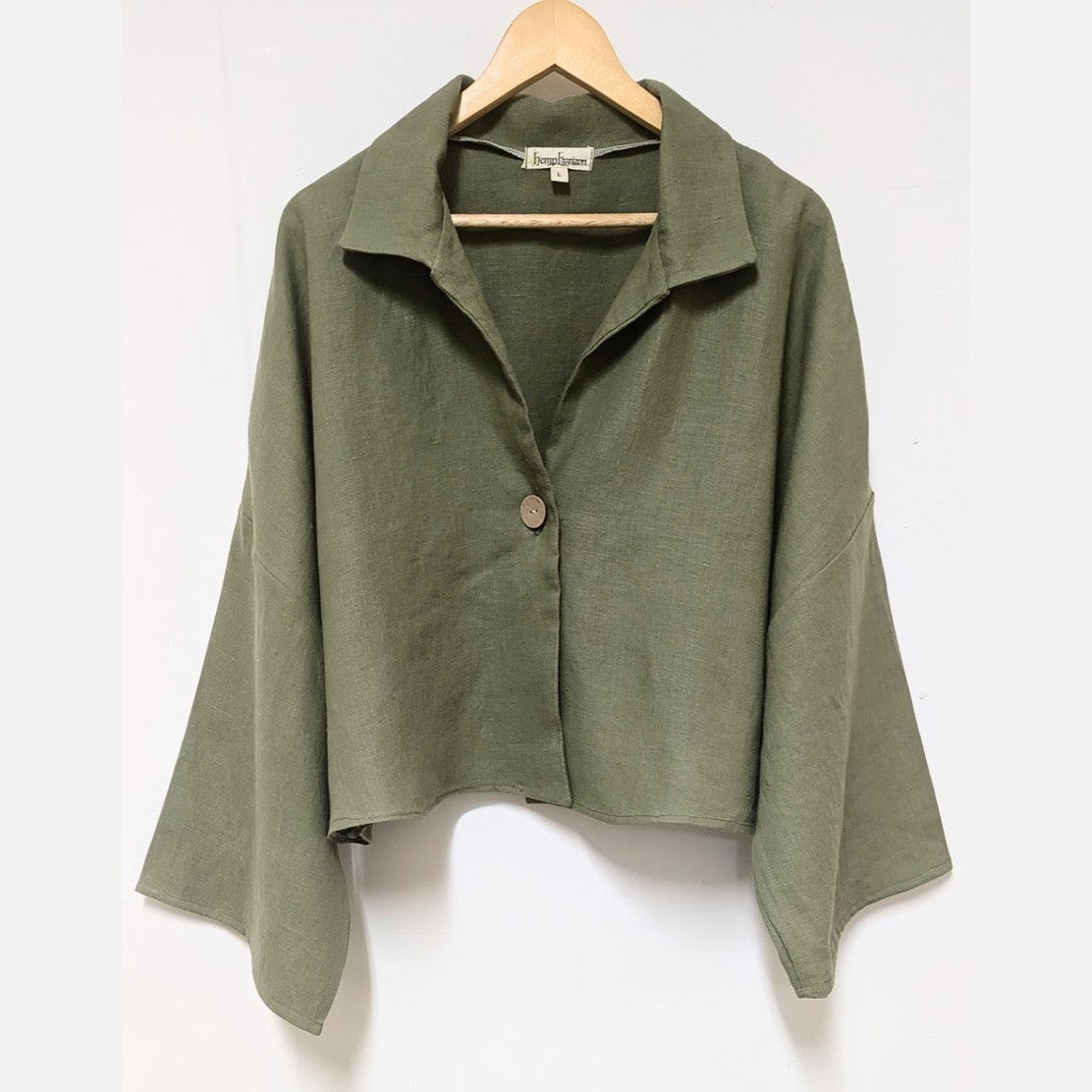 Green hemp shirt top on a hanger against a white background
