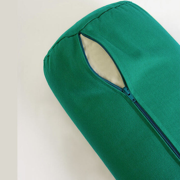 Green yoga bolster with a zipper on a beige background