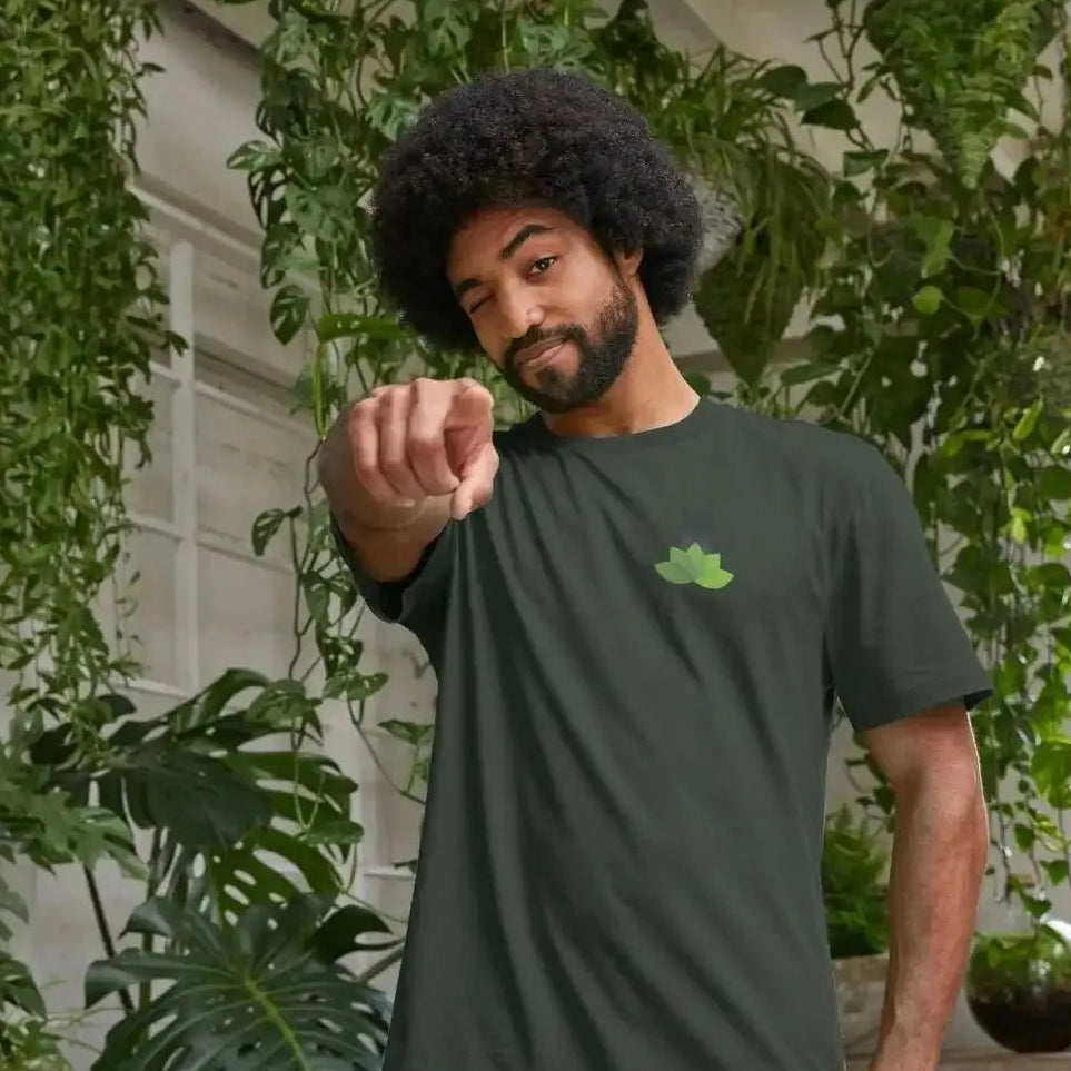 Man wearing a dark green t-shirt with a logo, standing in front of greenery