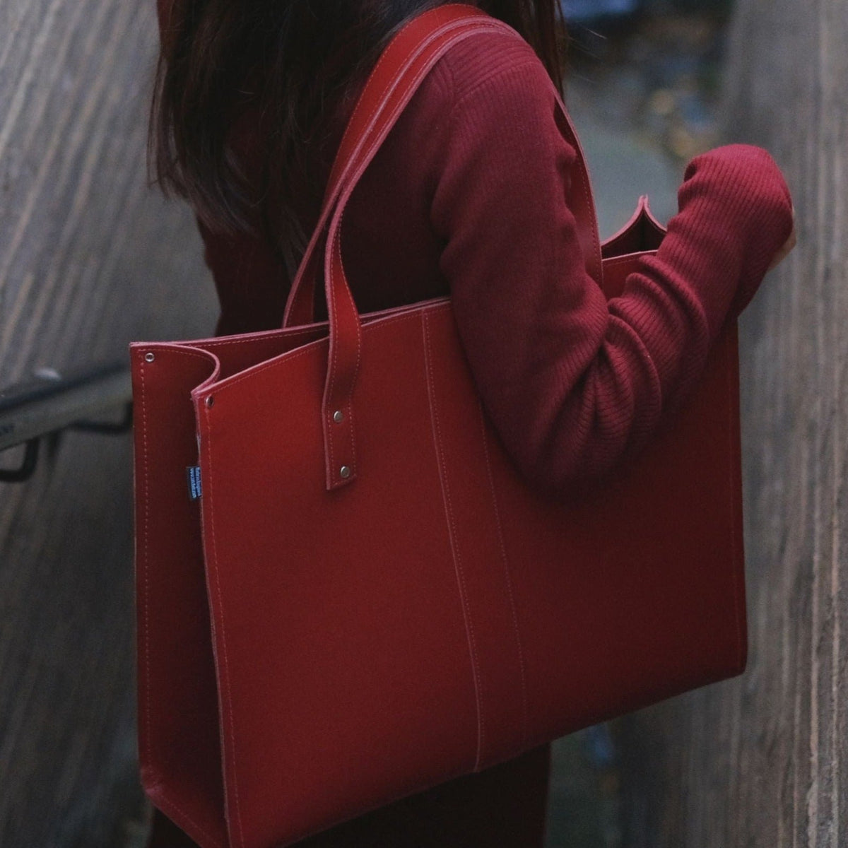 Person holding a red tote bag with a blurred background