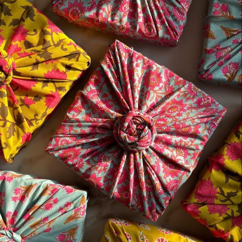 Colorful fabric-wrapped presents with floral patterns on a wooden surface