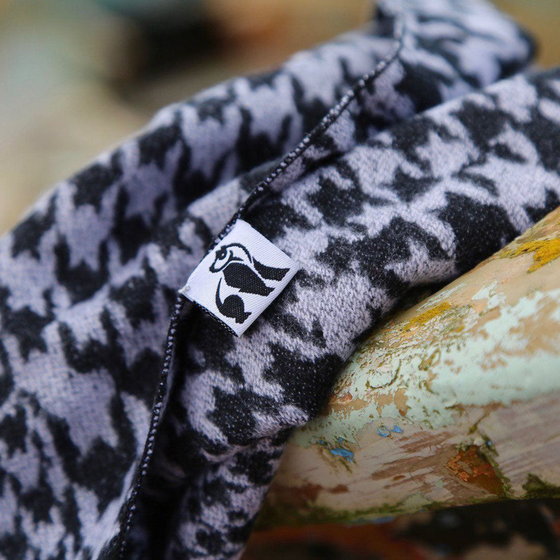 A close-up shot of a black and white men's scarf with a brand label on a textured surface