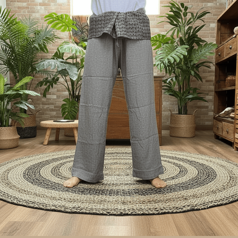 Person wearing grey yoga trousers standing in a room with wooden furniture and plants.