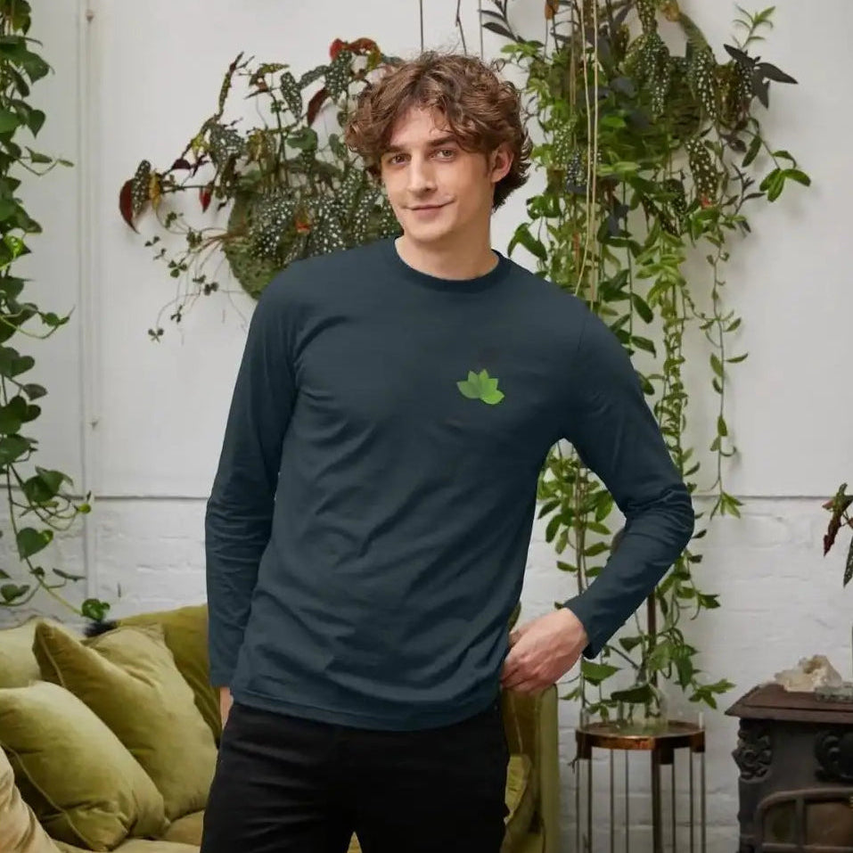 A man wearing a dark long-sleeve shirt with a green logo in a room with plants and a couch.